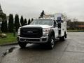 A 2015 Ford F-550 truck with a utility body and ladder on top is parked with the front facing the viewer