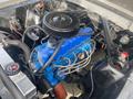 Engine compartment of a 1966 Ford Mustang featuring a blue engine block with black air filter and various wires and hoses visible