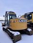 A 2009 John Deere 135 D excavator with a yellow exterior and black tracks parked on snow-covered ground