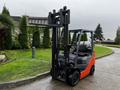 A 2017 Toyota 8FCGCU25 forklift with a grey and orange body and an upright mast is positioned on a path surrounded by greenery