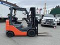 A 2011 Toyota Forklift with an orange and gray exterior featuring two long forks at the front and a seated driver's area