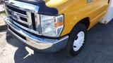 2015 Ford Econoline with a yellow body and chrome accents shown from the front highlighting the headlights and wheel