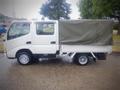 A 2003 Toyota Toyoace truck with a white cab and a covered cargo area in green fabric