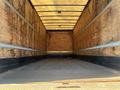 The interior of a 2013 International 4300 box truck showing wooden walls and a gray floor with no cargo inside