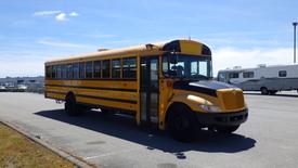 A 2014 International 3000 school bus with a yellow exterior and large windows is parked on a paved area