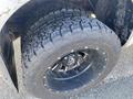 Close-up of a rugged tire mounted on a black wheel with a shiny rim designed for a 2000 Ford F-350 SD