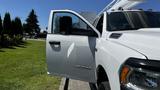 A white 2019 RAM 3500 pickup truck with an open driver's door showcasing the vehicle's sleek design and prominent RAM logo on the side