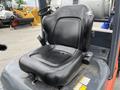 A black seat of a 2011 Toyota Forklift with a curved design and adjustable armrests