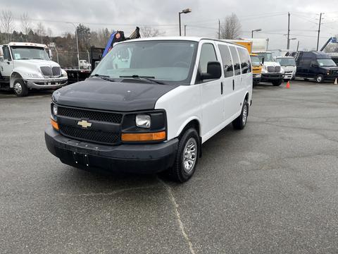 A 2012 Chevrolet Express van with a black front hood and white body facing forward on a parking lot