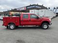 A red 2011 Ford F-250 SD with a utility bed and side steps is parked in a commercial area