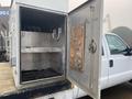 A 2009 Ford F-450 SD with an open metal utility box revealing shelves and hooks inside