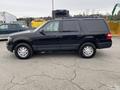 A black 2017 Ford Expedition parked on a pavement showing its side profile with black windows and steel wheels