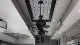 A ceiling fan with black blades and a black light fixture hangs from a patterned ceiling in a 2021 Forest River Cedar Creek trailer