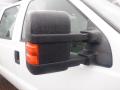 A close-up of the side mirror of a 2009 Ford F-450 SD with raindrops on its surface and a red marker light attached