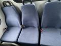 Three blue fabric seats with seatbelts inside a vehicle