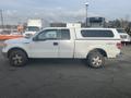 White 2009 Ford F-150 pickup truck with an extended cab and a truck bed cover on the back parked on a lot