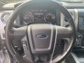 Steering wheel of a 2014 Ford F-150 with controls for audio and cruise features visible