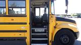 A 2014 International 3000 school bus with a yellow exterior and an open door showing the driver's seat and interior steps