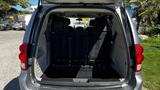 A 2016 Dodge Grand Caravan with its rear trunk open showing a spacious interior and folded rear seats