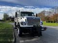 A white 2011 International 7500 truck with a prominent grille and a plow attachment at the front parked on the side of a road