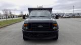 Front view of a 2008 Ford F-450 Super Duty truck in dark color with a flatbed and multiple amber lights on top