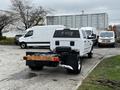 A white 2018 RAM 3500 truck with an open bed and spare tire visible in the rear parking lot among other vehicles