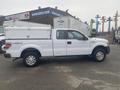 A white 2013 Ford F-150 with a truck bed cap parked sideways showing its four-door design and Lariat trim details