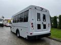 A gray 2015 Chevrolet Express shuttle bus with large windows and rear entry doors