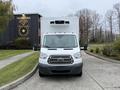 A 2018 Ford Transit van with a white body and gray front facing the camera