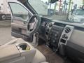 Interior of a 2009 Ford F-150 featuring a steering wheel with a cover dashboard controls and a center console