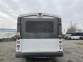 A 2017 Chevrolet Express bus with a gray and white exterior parked with its rear facing the viewer