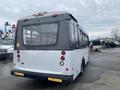 A 2017 Chevrolet Express bus with a white body and black accents viewed from the rear showing taillights and large window panels