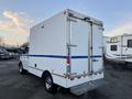 A white 2009 GMC Savana cargo van with double rear doors and a blue stripe on the side