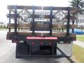 A 2015 International 4400 truck with a flatbed and wooden railings displaying a railroad crossing sign on the back