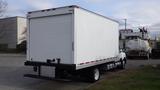 A 2012 International TerraStar truck with a large white cargo box and a dual rear axle is parked on a street