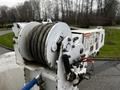 A close-up of a winch on a 2011 Western Star Trucks 4900 featuring a metal drum with rope coiled around it and a series of control levers and warning labels