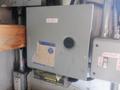 A gray electrical junction box with a round black knob and a label that reads 12 VOLT attached to a wooden structure with wires and other equipment around it