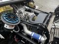 Close-up of the engine compartment of a 2005 Freightliner M2 106 featuring various components like the air filter and cooling system with blue and gray hoses