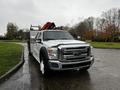 White 2014 Ford F-550 pickup truck with a flatbed and tools in the truck bed