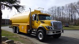 A yellow 2010 International 7500 Tandem truck with a large tank mounted on the back and prominent safety markings on the side