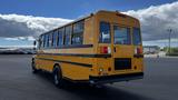 A yellow 2014 Freightliner Thomas diesel school bus viewed from the rear with large windows and a black bumper