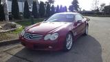 A red 2003 Mercedes Benz sports car with a sleek design and chrome wheels parked on a concrete surface