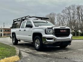 A white 2018 GMC Sierra 1500 pickup truck with a black roof rack parked on a concrete surface