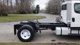 A 2003 Freightliner M2 106 truck with a white cab and black chassis visible from the side featuring a single rear wheel and exposed frame components