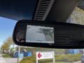 A rearview mirror displaying a camera feed with a warning to check entire surroundings