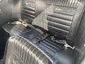 Interior seating of a 1966 Ford Mustang with black leather upholstery featuring vertical stripes and seatbelts