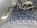 Close-up of the tire and suspension system of a 2013 Ford F-150 showing the tread pattern and components underneath the vehicle