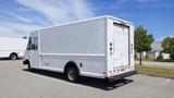 A 2011 Ford Econoline cargo van with a white exterior parked in a lot featuring a boxy design and rear loading door