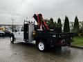 A 2014 Ford F-550 truck with a flatbed and a mounted crane on the rear side