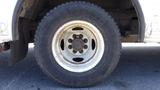 Close-up of the wheel of a 2011 Ford Econoline featuring a white rim and a thick black tire with visible tread and dirt marks